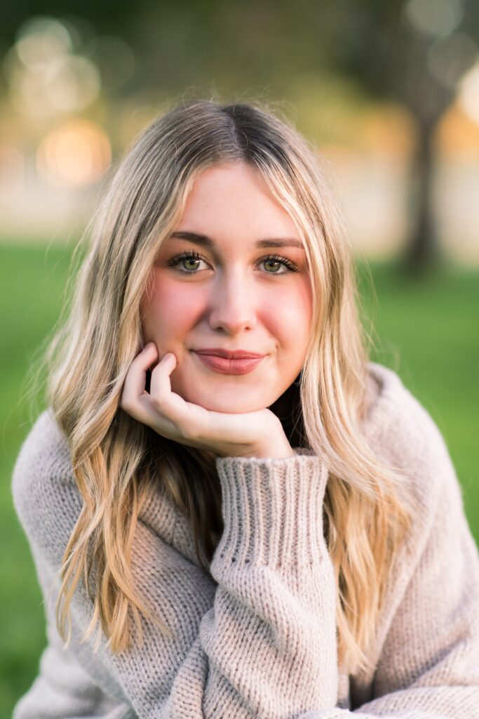 Senior girl with blond hair wearing a brown sweater looking directly into the camera