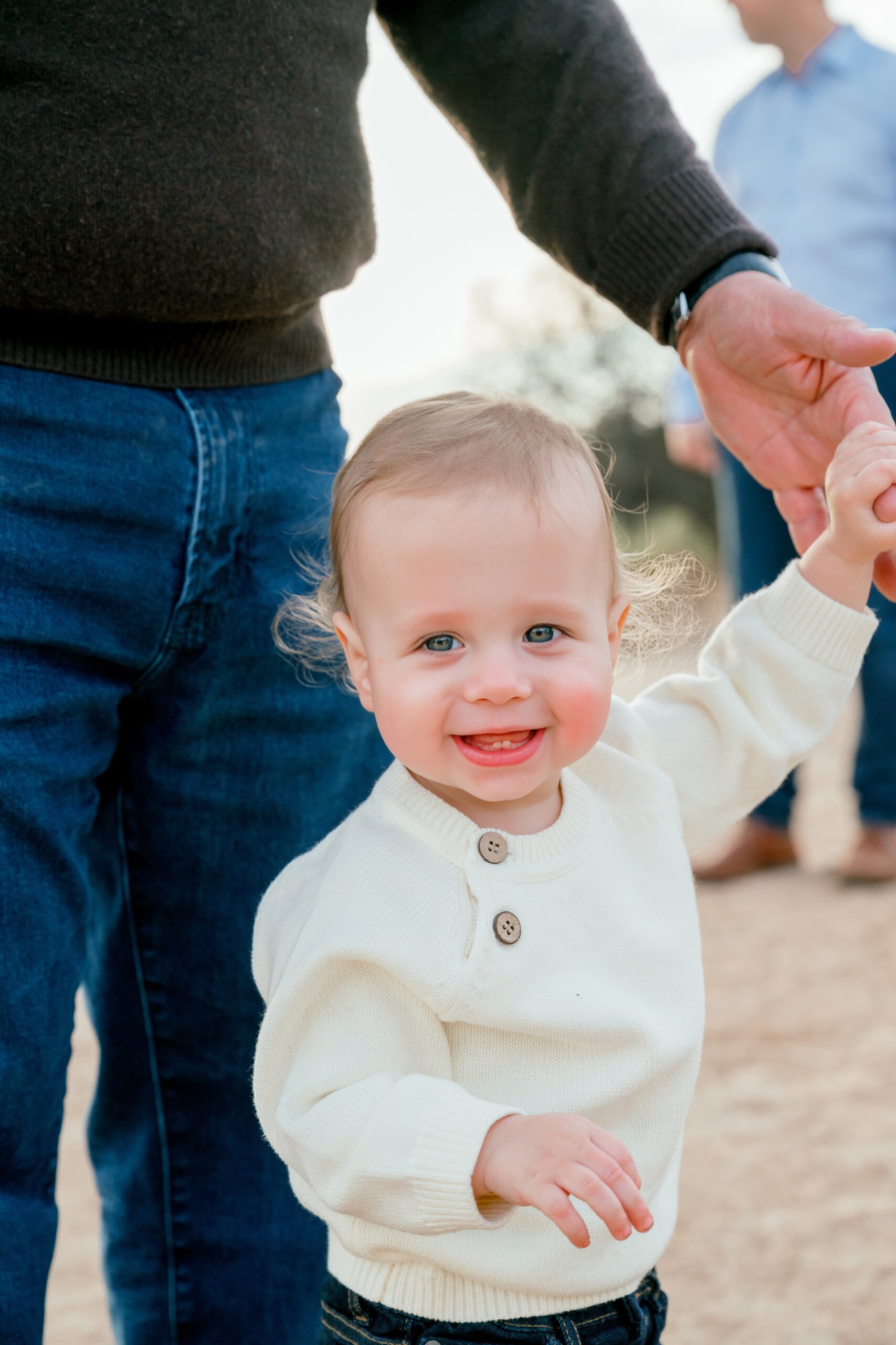A smiling toddler is helped by dad to walk a trail during scottsdale kid activities