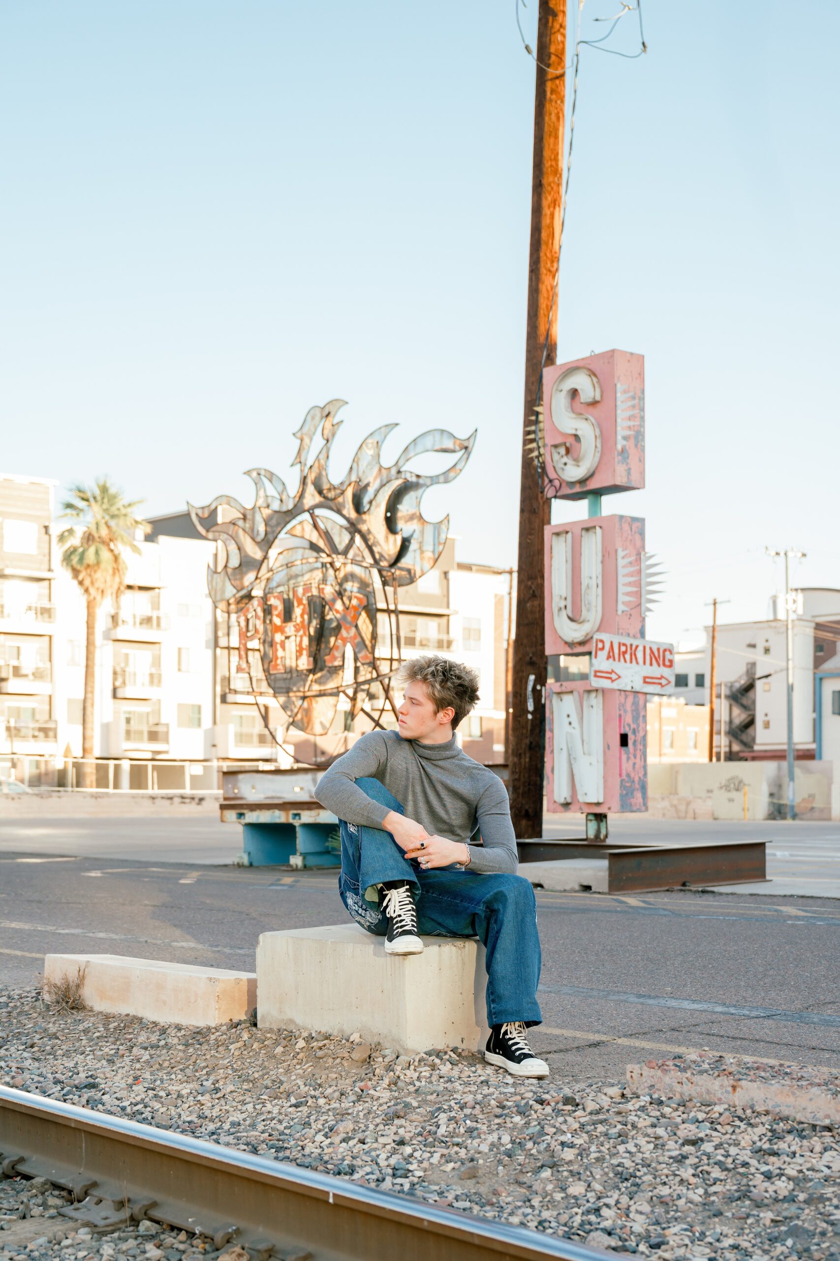 A high school senior sits on a concrete block in a Phoenix art district for urban senior photos