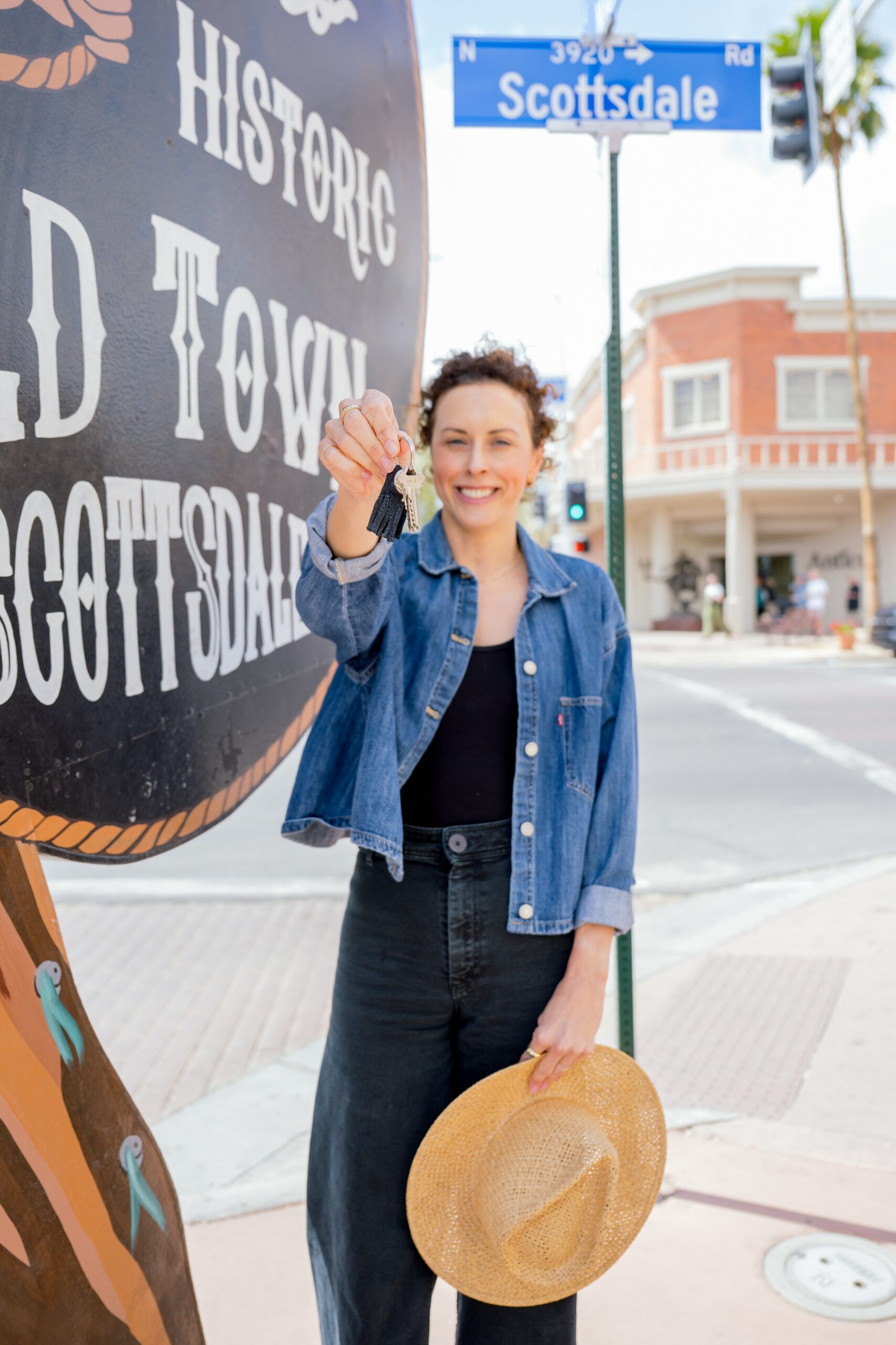 A woman holds out her keys on a street corner in a denim jacket at one of the old town scottsdale photo spots