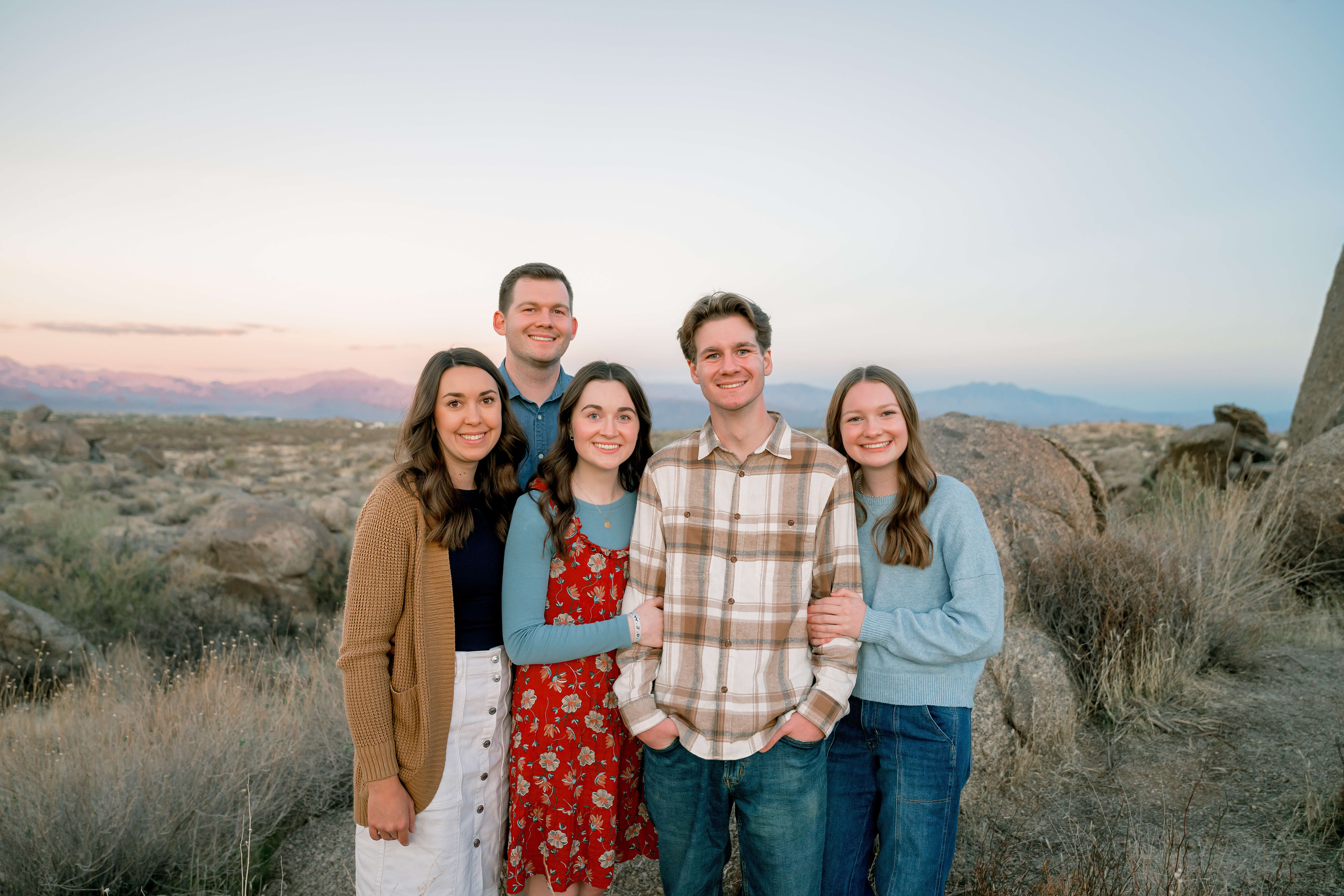 A smiling family of five with three teens at sunset in the desert while on a hike during things to do with kids in phoenix