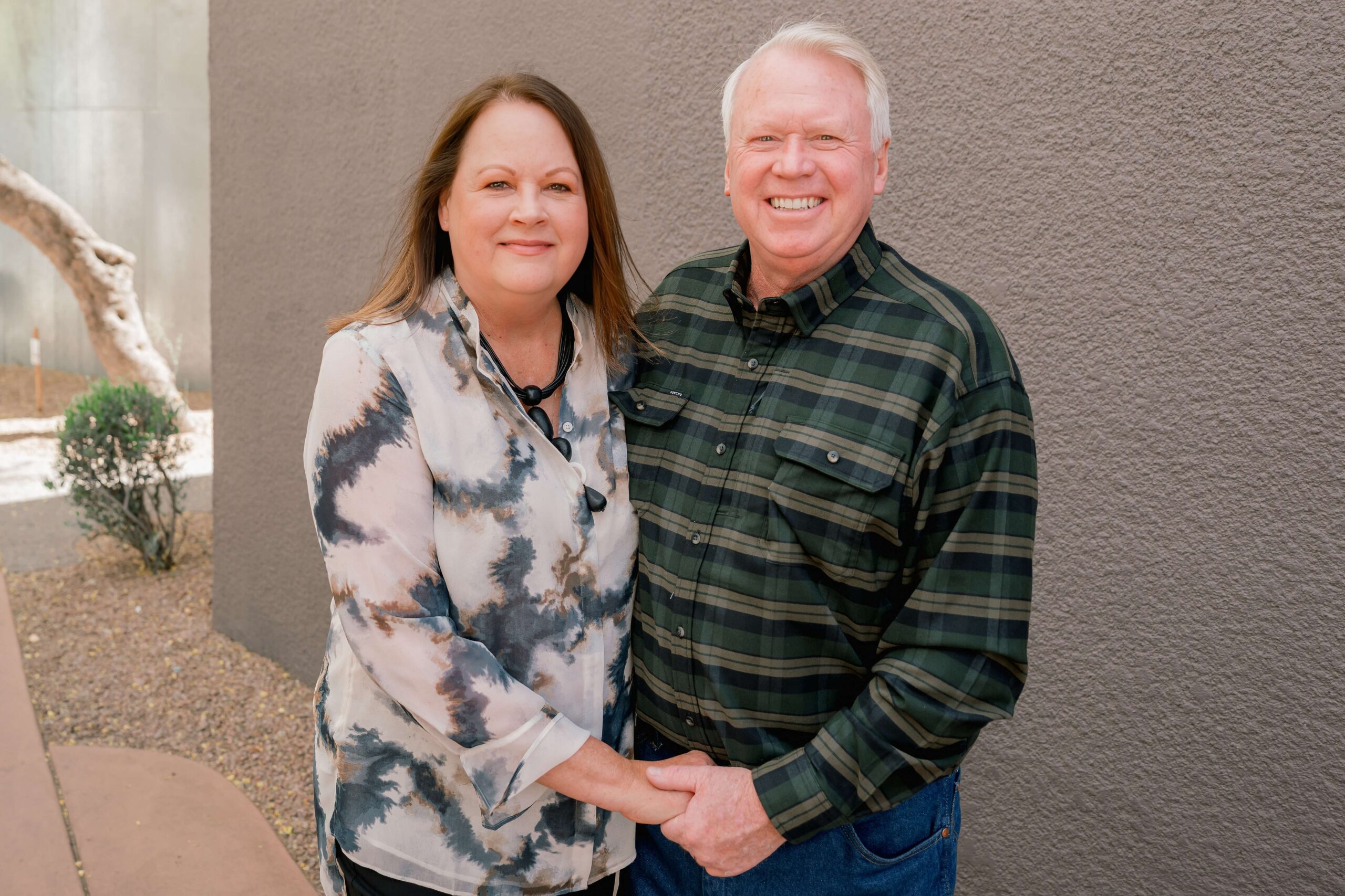 Smiling Mom and dad in green and white stand holding hands in an alley before enjoying family things to do in phoenix at night