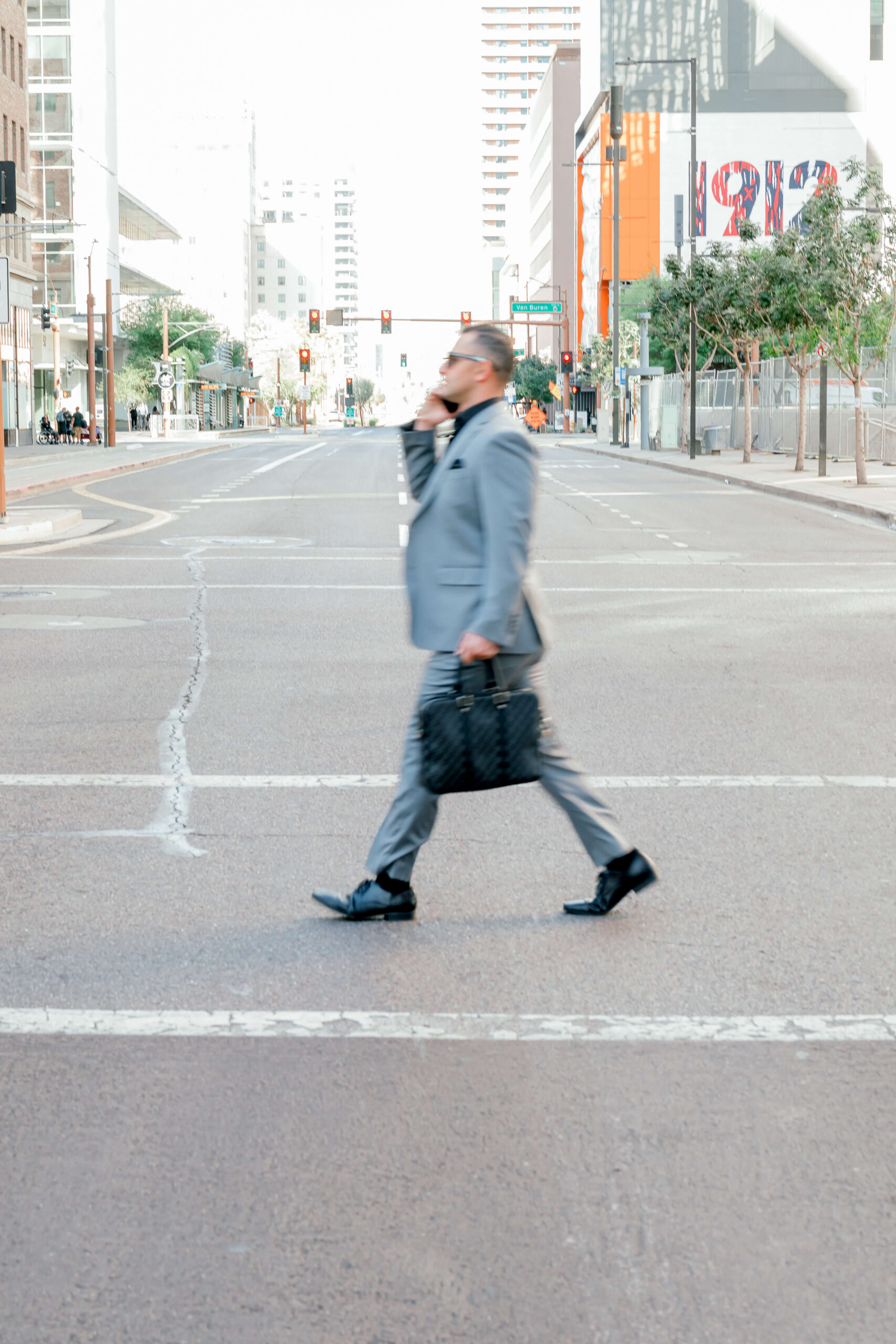 A busy man in a grey suit walks on the street on the phone